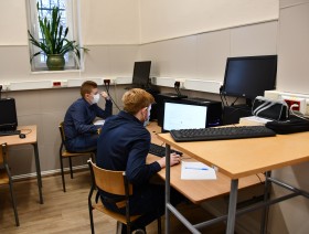 Dwóch uczniów siedzi przed ekranami komputerowymi rozwiązując test